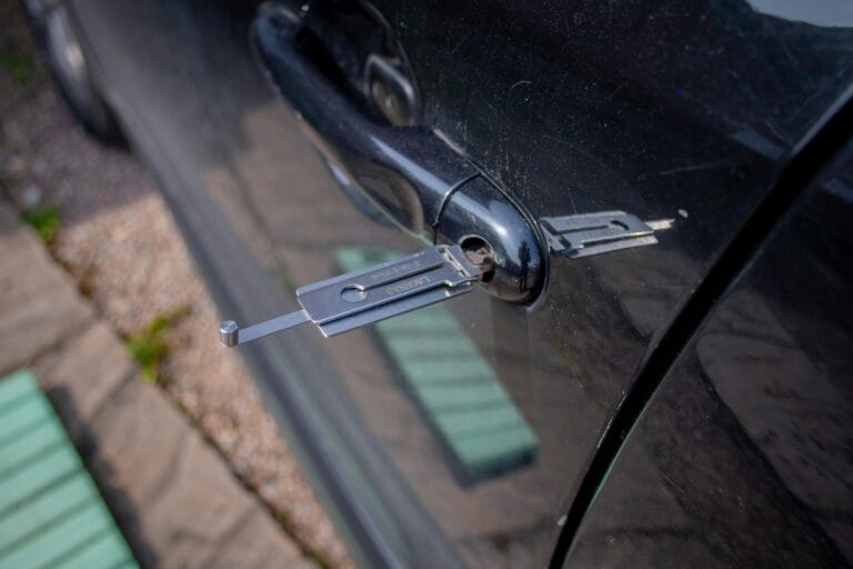 Your Home Needs Lock Repair in Englewood,Close-up of a locksmith tool inserted into a car door lock, demonstrating security access.